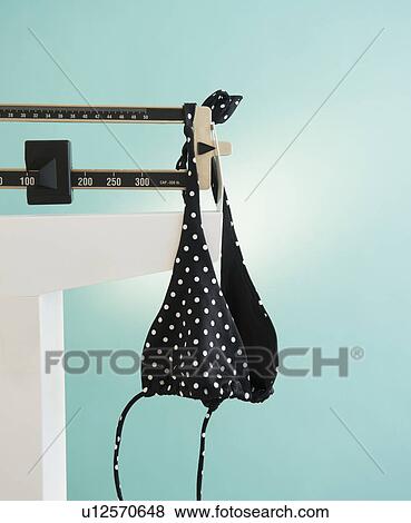 Stock Photo - Bikini hanging on weight scale. Fotosearch