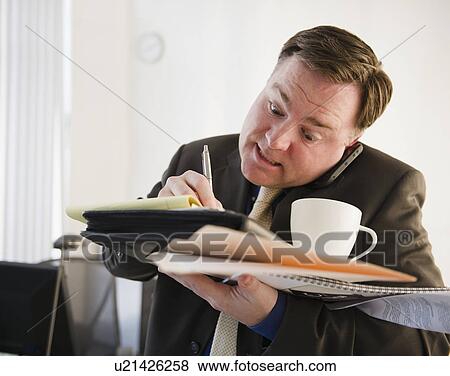 Businessman writing and talking on phone View Large Photo Image Stock Photo - Businessman writing and talking on phone. Fotosearch