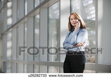 Businesswoman talking on phone in corridor View Large Photo Image Stock Image - Businesswoman talking on phone in corridor. Fotosearch