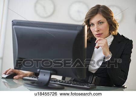 Stock Photograph - Businesswoman working at desk in office. Fotosearch