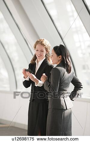 Stock Photography - Businesswomen looking at cell phone. Fotosearch