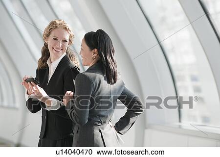Stock Image - Businesswomen using at cell phone. Fotosearch