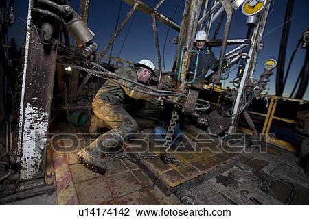 Stock Image - Canada, Alberta, Oil workers using oil drill. Fotosearch