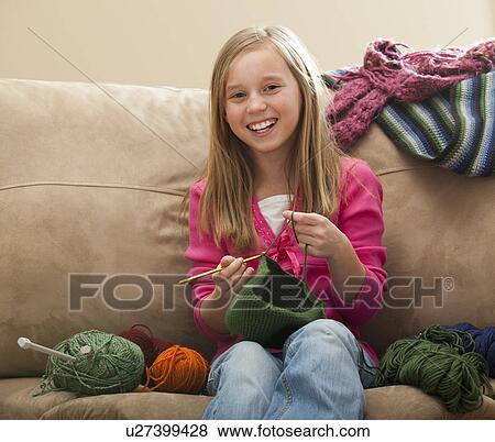 Stock Photo - Cheerful girl (8-9) knitting woolly hat. Fotosearch
