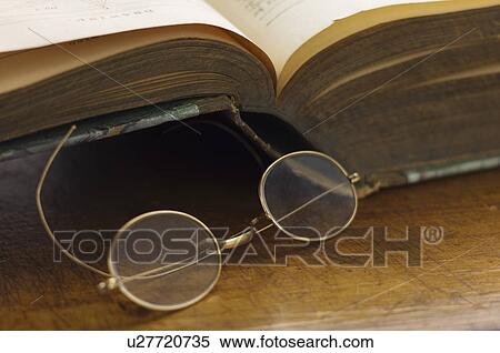 Stock Photography - Close up antique round glasses and open book. Fotosearch