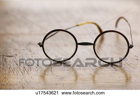 Stock Image - Close up antique round glasses on wooden table. Fotosearch
