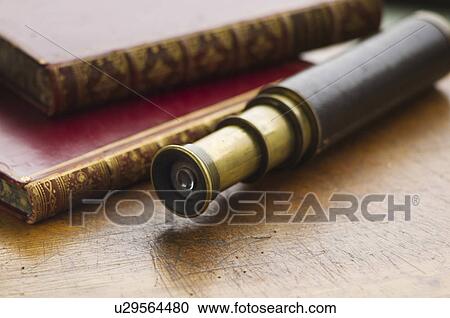 Stock Image - Close up of antique books and telescope. Fotosearch