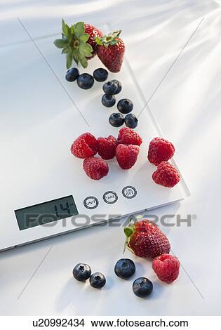 Picture - Close up of berries on kitchen scale. Fotosearch