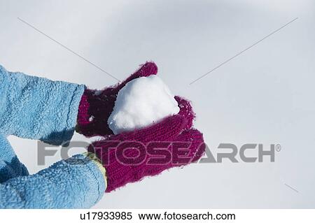Stock Photography - Close up of girl's (6-7) hands in mittens holding snowball. Fotosearch