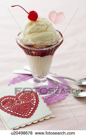 Stock Photo - Close up of ice cream dessert with cherry on top and heart shaped cut-out. Fotosearch
