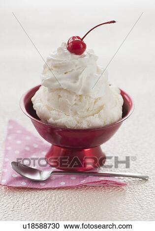 Stock Image - Close up of ice cream with cherry on top. Fotosearch