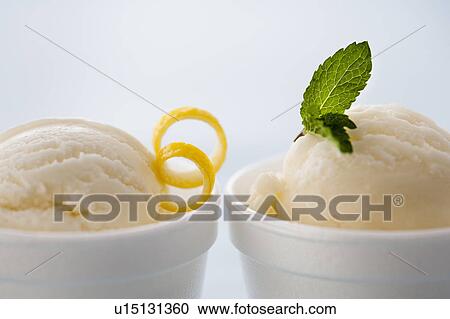 Stock Image - Close up of ice cream with lemon peel an mint leaf. Fotosearch