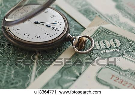 Stock Image - Close up of pocket watch and shares. Fotosearch
