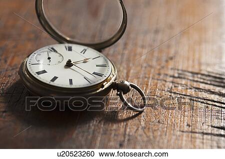 Stock Image - Close up of pocket watch on scratched table. Fotosearch