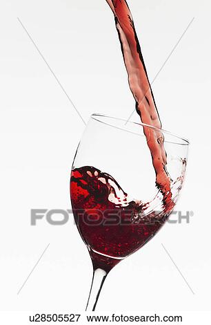 Stock Photo - Close up of red wine being poured into glass on white background. Fotosearch