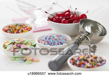 Stock Photo - Close up of scoop and bowls with colorful toppings for ice creams. Fotosearch