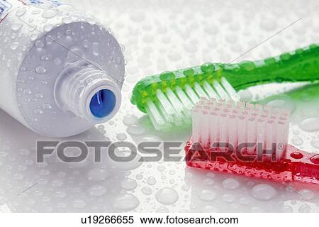 Stock Photography - Close-up of toothpaste and toothbrushes covered with water drops. Fotosearch