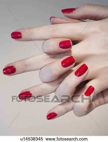 Stock Photography - Close up of woman's clasped hands with red nail polish. Fotosearch