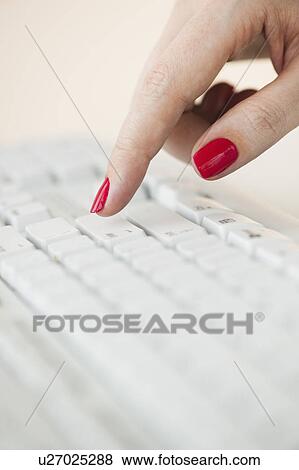 Stock Photo - Close up of woman's finger with red nail polish typing on computer keyboard. Fotosearch