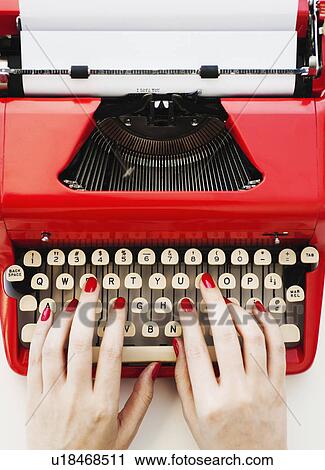 Stock Image - Close up of woman's hands with red nail polish typing on antique typewriter. Fotosearch