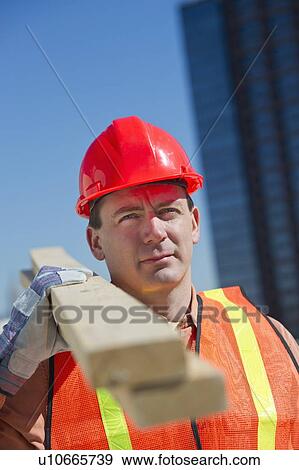 Stock Photo - Construction worker carrying planks. Fotosearch