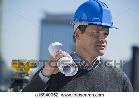Stock Image - Construction worker holding rolled up blueprint. Fotosearch