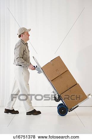 Delivery man pushing hand truck View Large Photo Image Stock Photo - Delivery man pushing hand truck. Fotosearch