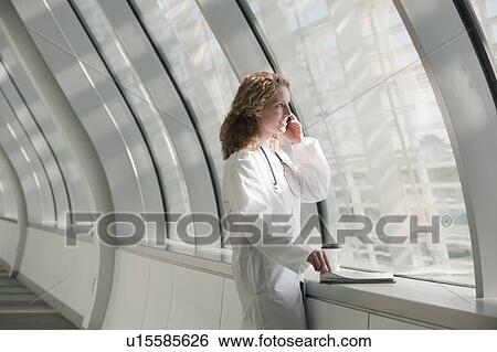 Stock Photograph - Doctor talking on phone in corridor. Fotosearch