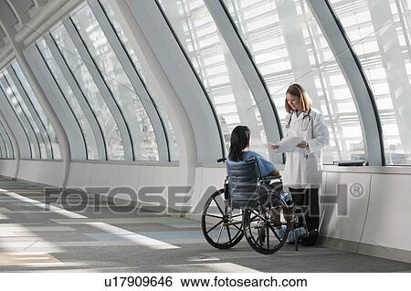 Stock Photograph - Doctor talking to patient in wheelchair. Fotosearch