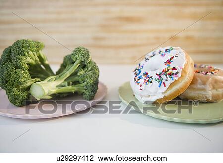 Stock Image - Donuts against broccoli. Fotosearch