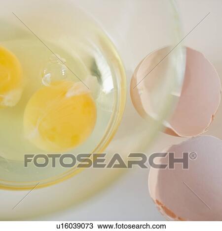 Stock Image - Egg yolks in bowl and egg shell on side. Fotosearch