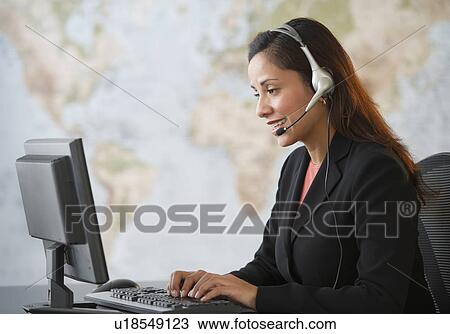 Stock Image - Female customer service representative with headset working on computer. Fotosearch