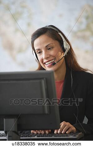 Stock Photography - Female customer service representative with headset working on computer. Fotosearch