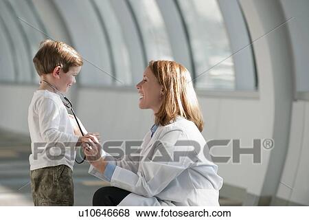 Female doctor talking to boy (6-7) in corridor View Large Photo Image Stock Photo - Female doctor talking to boy (6-7) in corridor. Fotosearch
