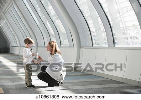 Female doctor talking to boy (6-7) in corridor View Large Photo Image Stock Photo - Female doctor talking to boy (6-7) in corridor. Fotosearch