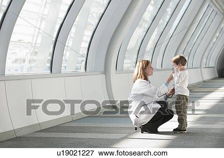 Female doctor talking to boy (6-7) in corridor View Large Photo Image Stock Photo - Female doctor talking to boy (6-7) in corridor. Fotosearch