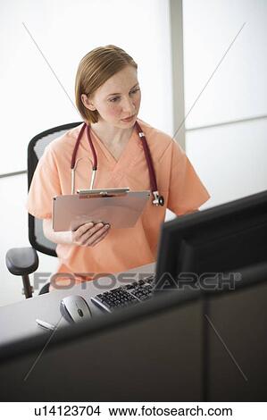 Female nurse reading medical records View Large Photo Image Picture - Female nurse reading medical records. Fotosearch