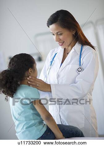 Stock Image - Female pediatrician examining girl (6-7) in doctor's office. Fotosearch