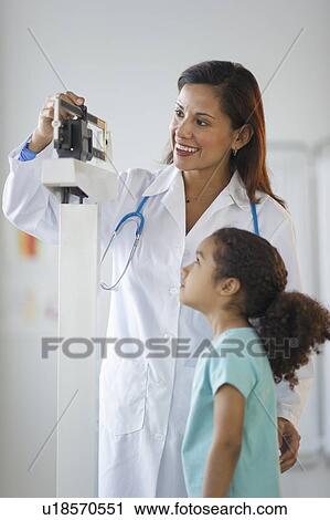 Stock Image - Female pediatrician examining girl (6-7) in doctor's office. Fotosearch