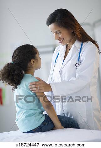 Stock Photo - Female pediatrician examining girl (6-7) in doctor's office. Fotosearch