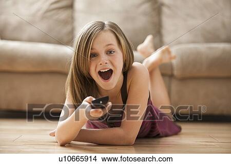 Picture - Girl (10-11) lying on floor, watching TV. Fotosearch