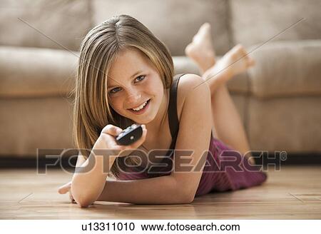 Girl (10-11) lying on floor, watching TV View Large Photo Image Stock Image - Girl (10-11) lying on floor, watching TV. Fotosearch