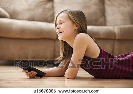 Girl (10-11) lying on floor, watching TV View Large Photo Image Stock Photography - Girl (10-11) lying on floor, watching TV. Fotosearch