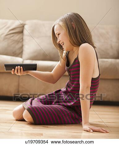 Girl (10-11) sitting on floor, watching TV View Large Photo Image Picture - Girl (10-11) sitting on floor, watching TV. Fotosearch