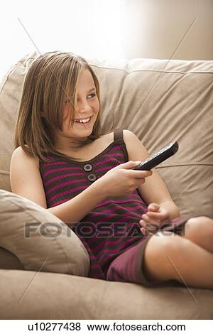 Girl (10-11) sitting on sofa, watching TV View Large Photo Image Stock Photo - Girl (10-11) sitting on sofa, watching TV. Fotosearch
