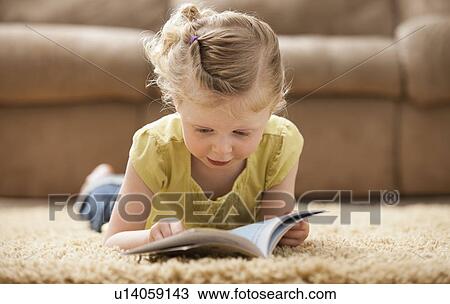 Girl (2-3) lying on rug, reading book View Large Photo Image Stock Image - Girl (2-3) lying on rug, reading book. Fotosearch