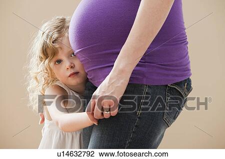 Girl (2-3) peeking form behind pregnant mother's belly View Large Photo Image Stock Image - Girl (2-3) peeking form behind pregnant mother's belly. Fotosearch