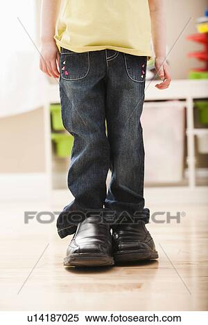 Stock Photography - Girl (2-3) standing in dad's shoes, low section. Fotosearch