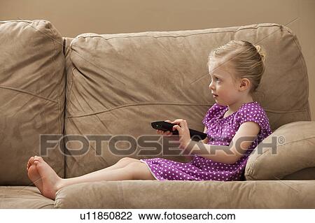 Stock Image - Girl (2-3) watching TV on sofa. Fotosearch