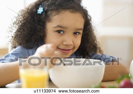 Picture - Girl (6-7) eating breakfast. Fotosearch